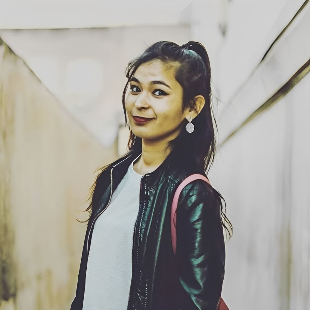 A man is sitting at a table holding a cup of coffee and using a laptop computer.