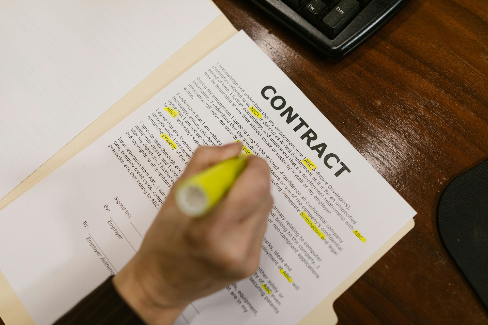 Hand highlighting clauses in a contract on a desk with a calculator nearby