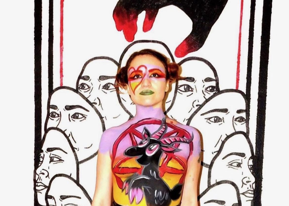 Brandi Johnson poses artistically in front of unique artwork.
