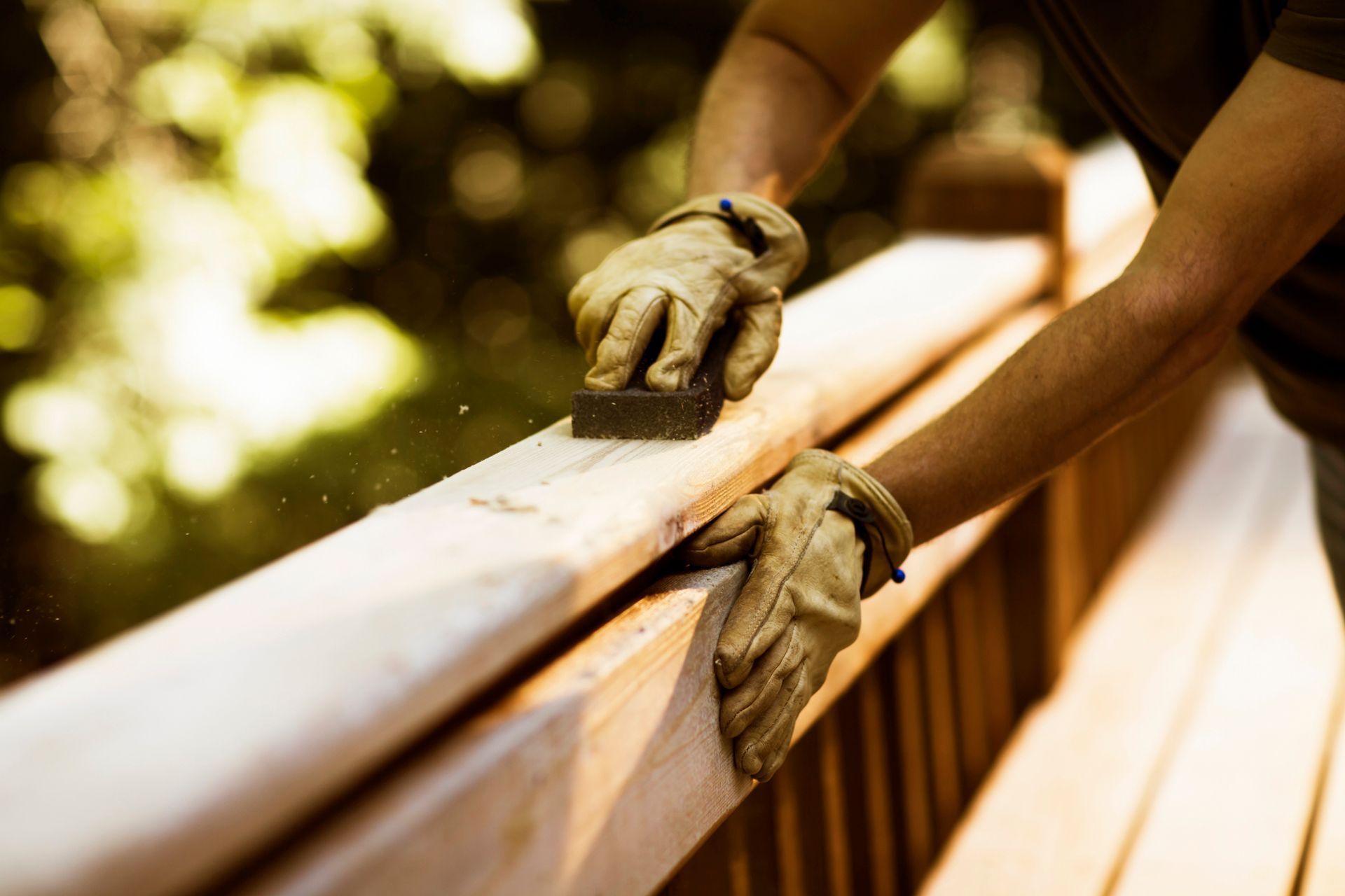 A person is sanding a wooden railing with a sponge.