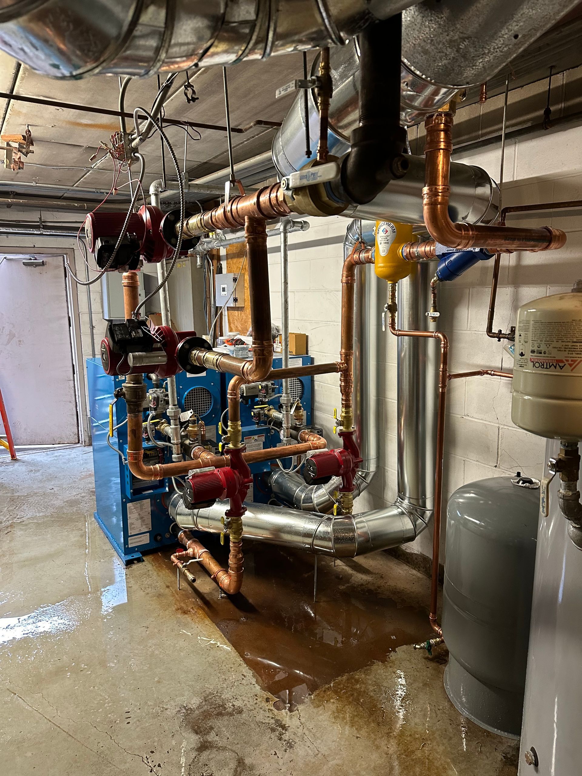 A room filled with lots of pipes and a blue boiler.