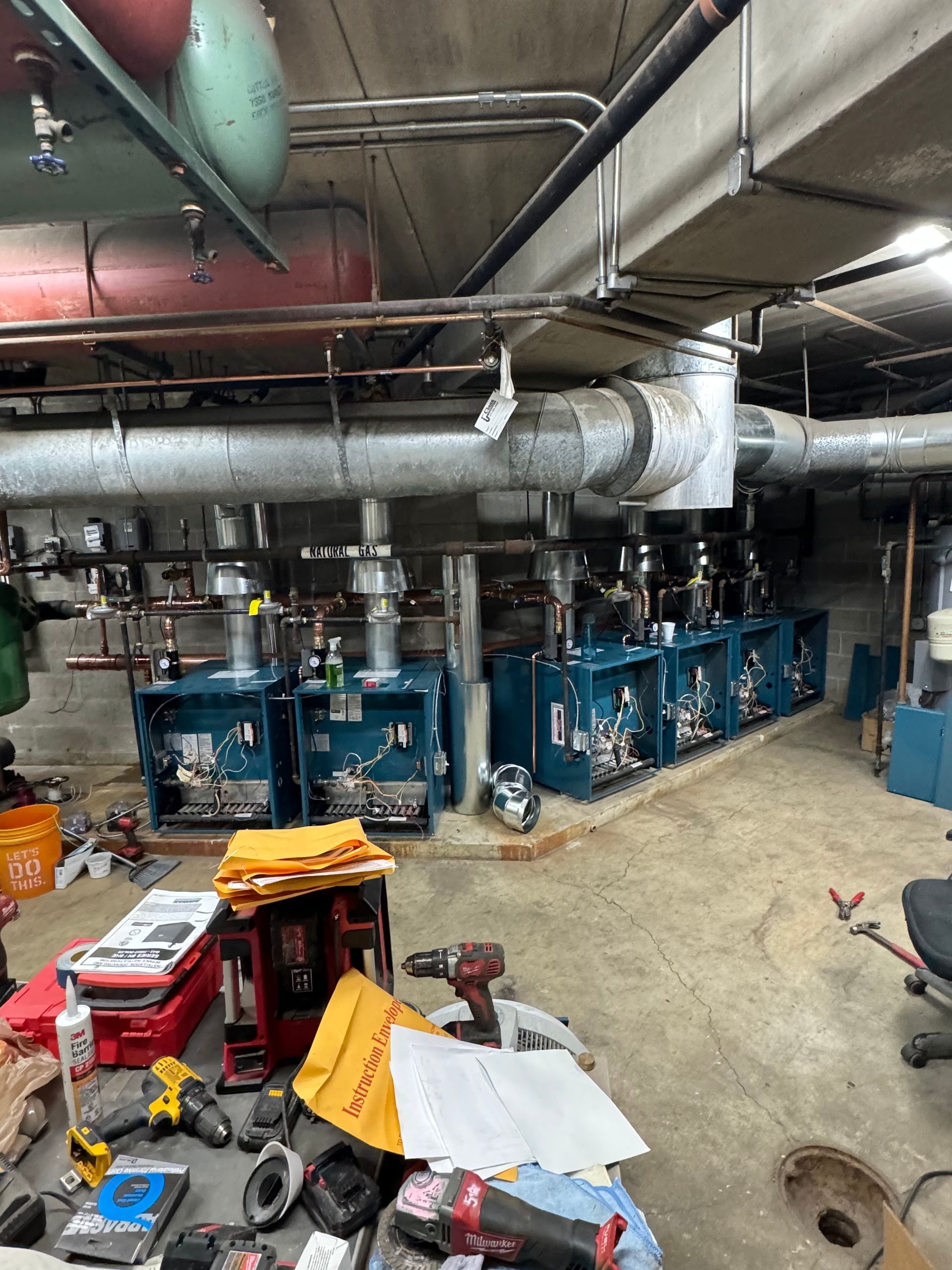 A messy room with a lot of pipes and tools on the floor.