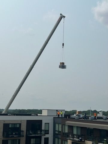 A large crane is lifting a large object over a building.