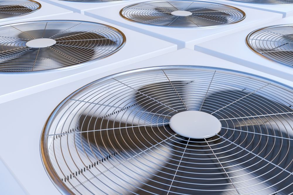 Large metal HVAC fans on a white rooftop, viewed from above