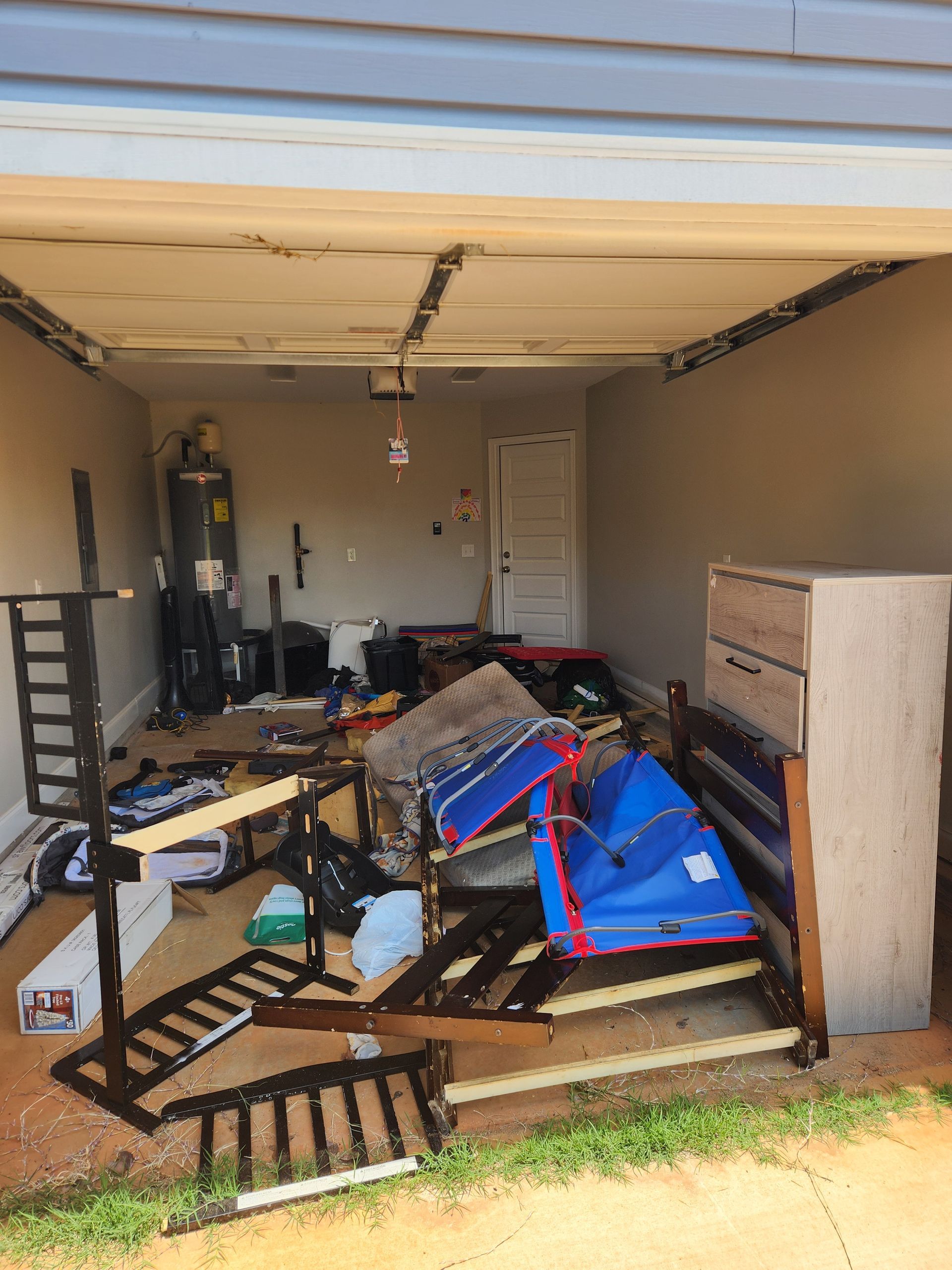Messy garage floor with scattered cardboard boxes, trash, and debris against a gray wall
