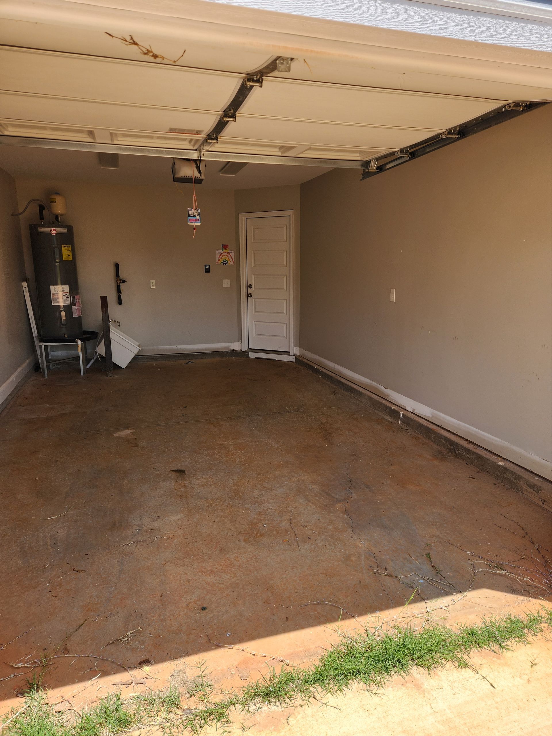 Empty gray garage with a concrete floor and closed overhead door opener.