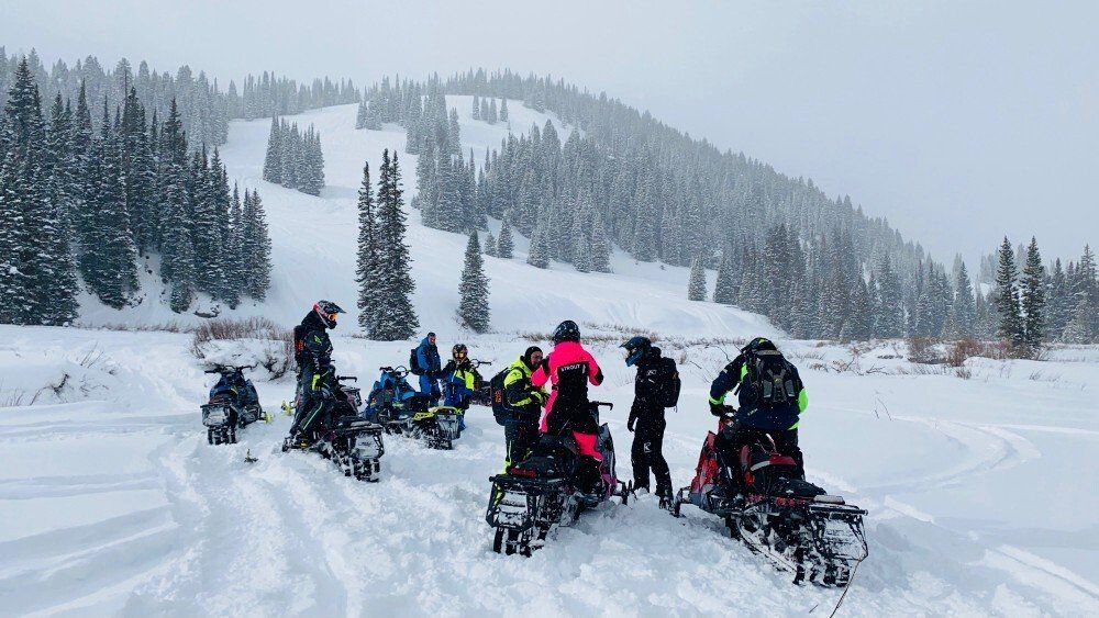 Group of snowmobile riders on mountain terrain in Utah
