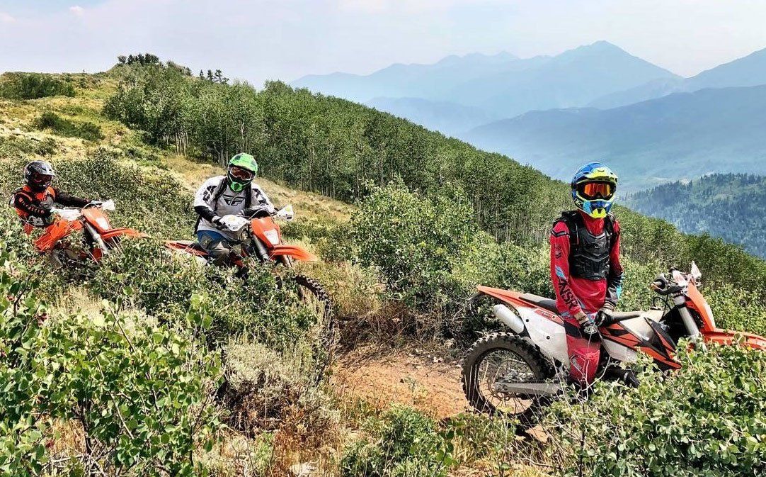 3 motorcycle riders standing on off-road single track trail in UT