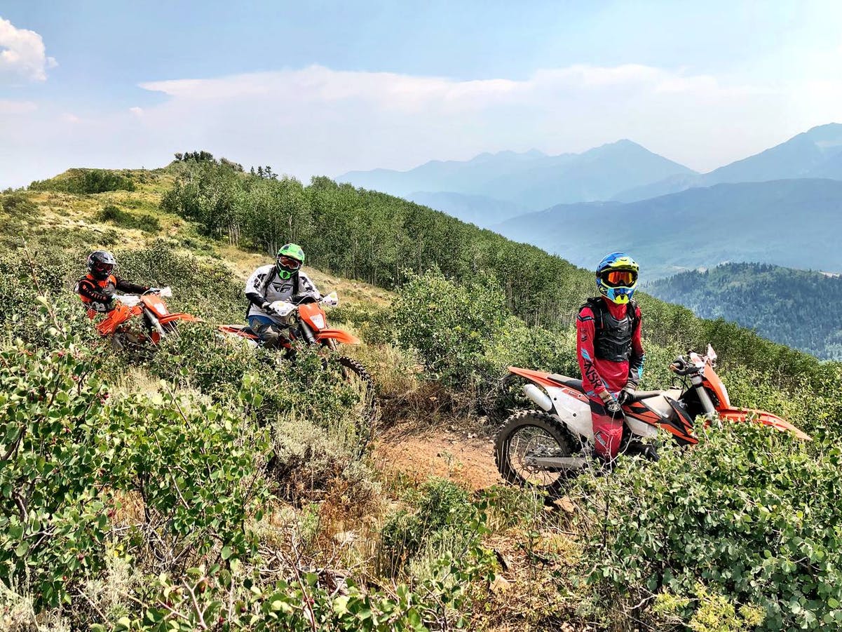 3 motorcycle riders standing on a single track off-road motorcycle trail in UT