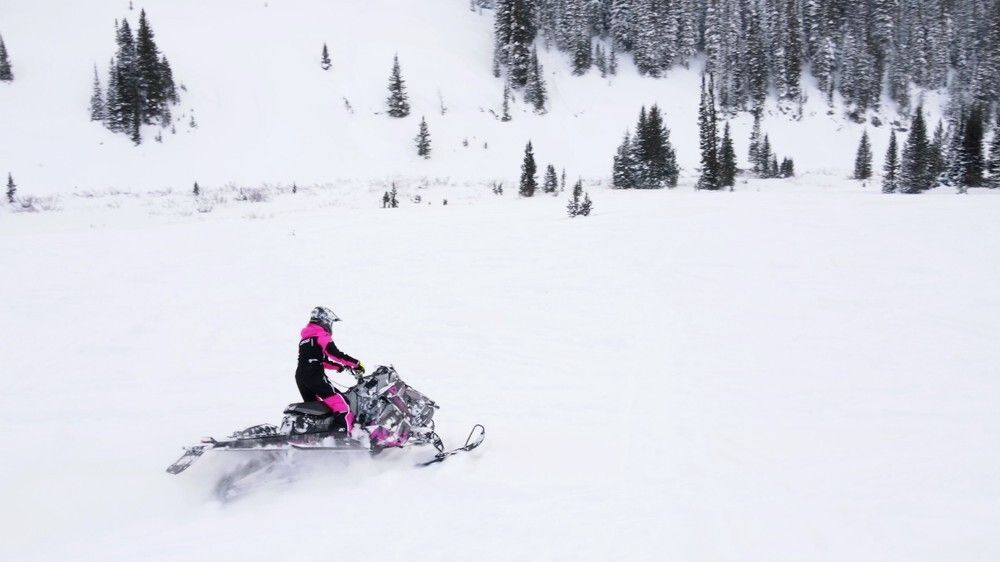 Female on snowmobile riding on mountain terrain in Utah