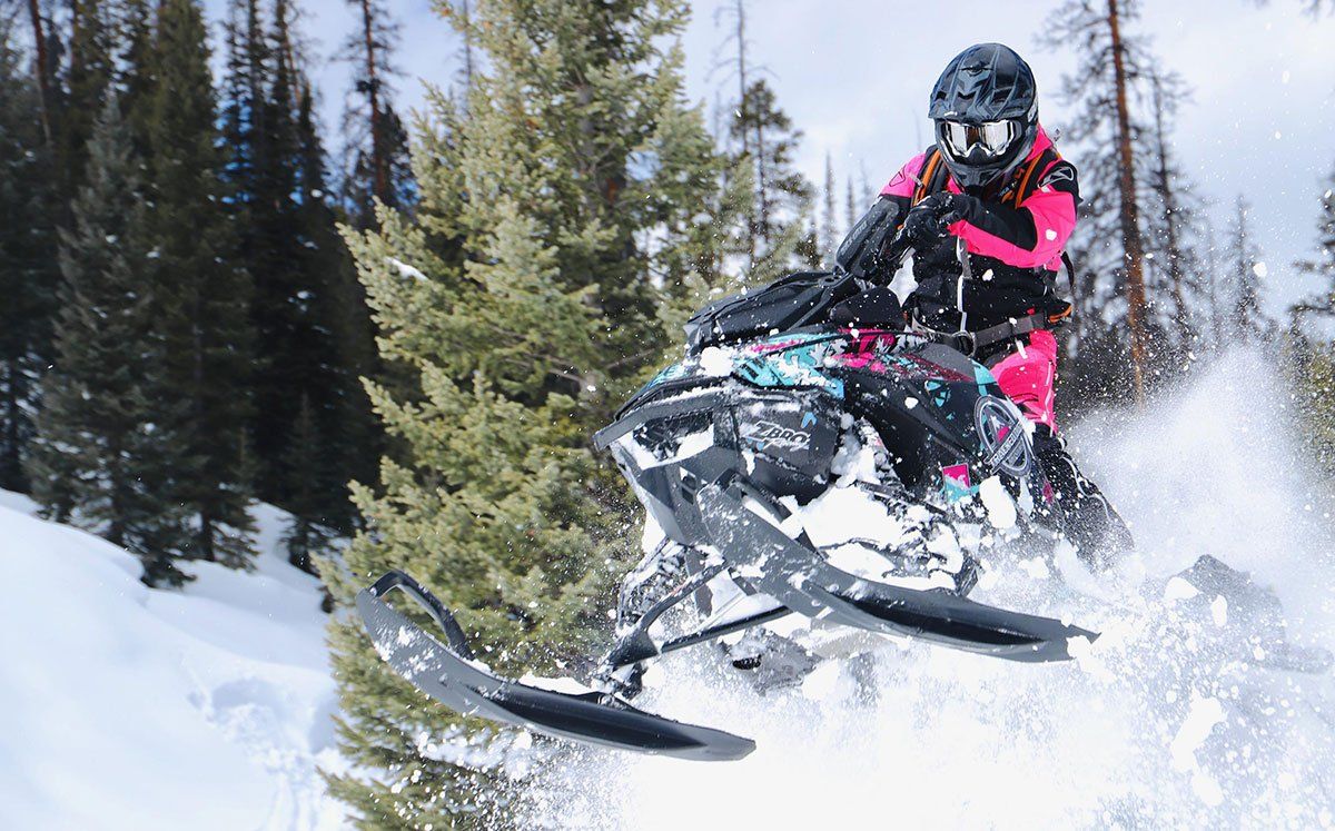 Snowmobile rider performing a jump stunt on snowmobile in Utah