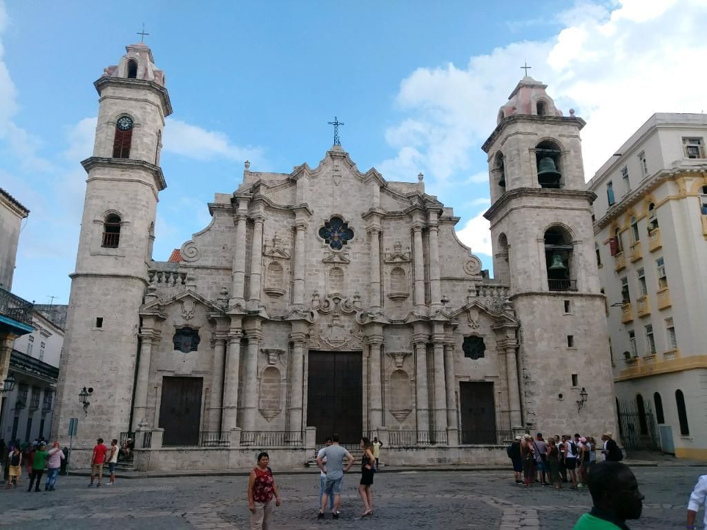Havana Cathedral, Cuba, with two bell towers, ornate facade, and plaza with people on a sunny day.