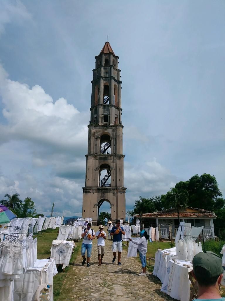 Tall tower with people walking toward it, on a grassy field with white fabric draped over structures.