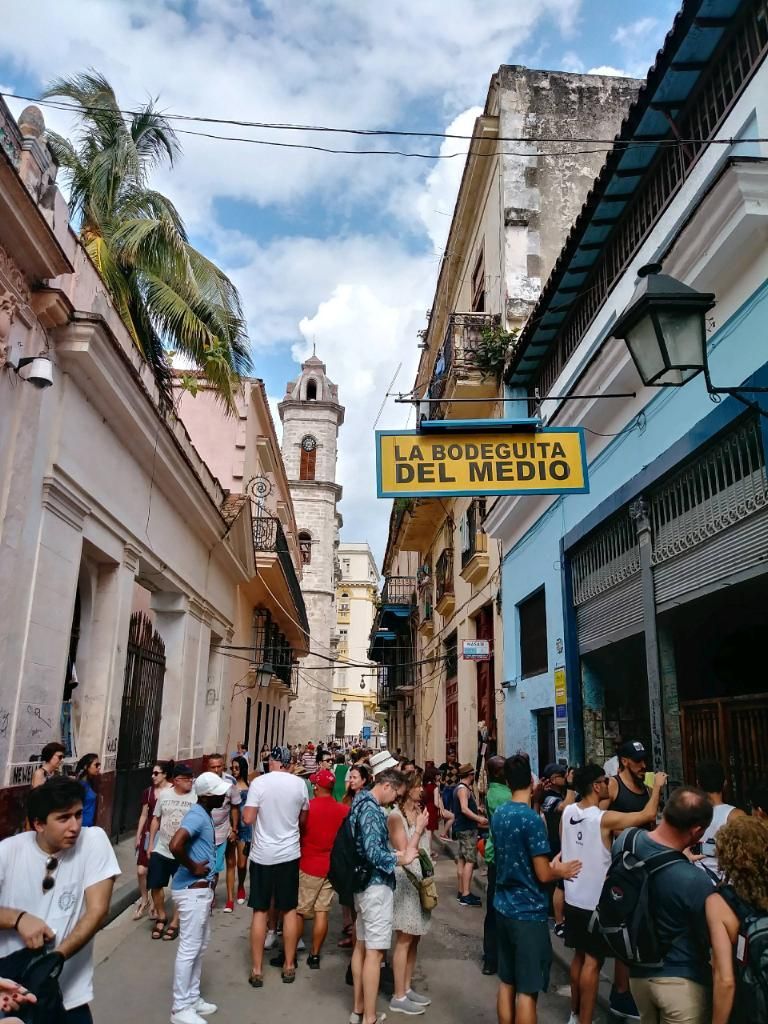 Street scene in Havana, Cuba, with a crowded alleyway leading to a sign reading 