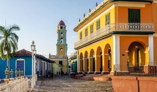 Colorful colonial buildings and church tower on cobblestone street in Trinidad, Cuba.