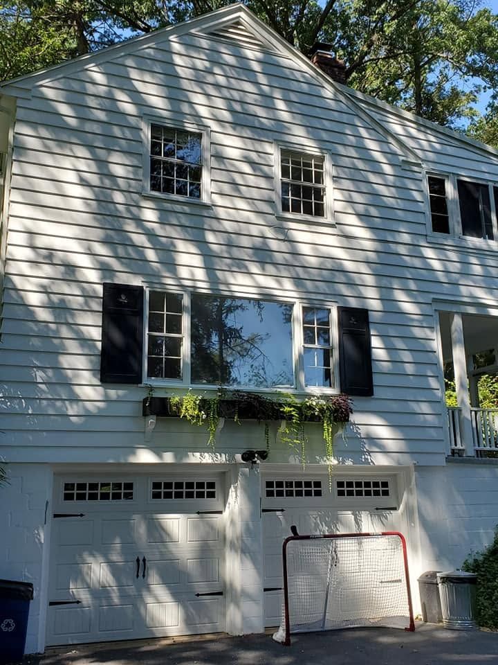 Two-story gray house with black shutters, garage doors, and a red soccer goal in front.