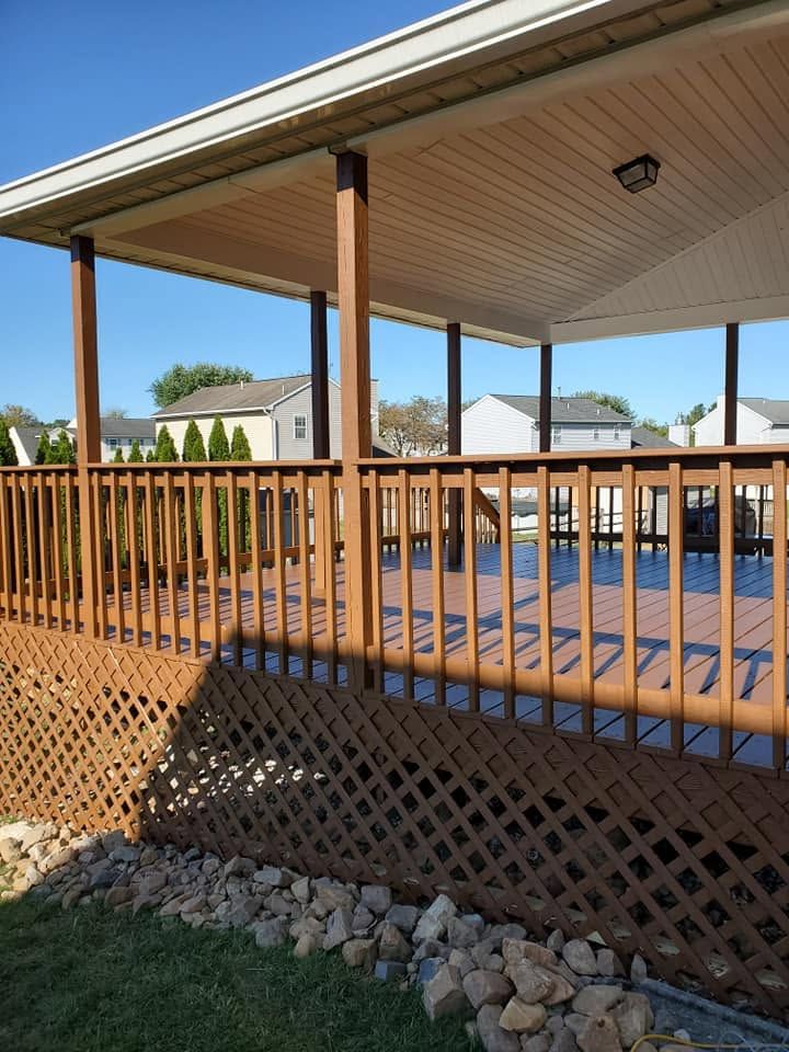 Wooden deck and covered patio beside a pool, with lattice skirting and stone landscaping.