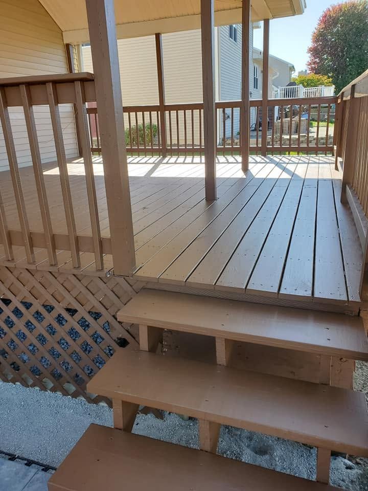 Wooden porch deck with steps, railing, and lattice under a house exterior.
