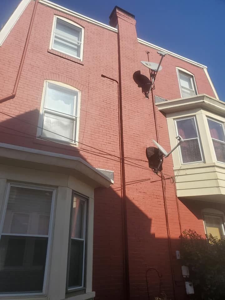Brick townhouse exterior with bay windows, a satellite dish, and clear blue sky