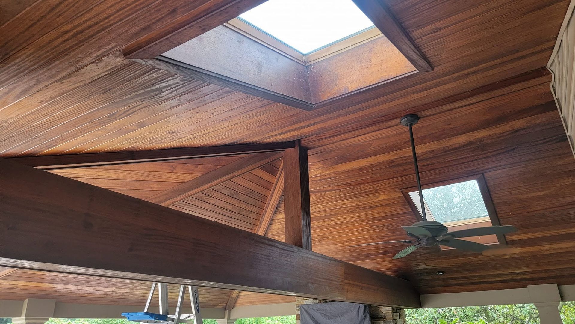 Wooden ceiling with skylights and a ceiling fan in a covered outdoor patio