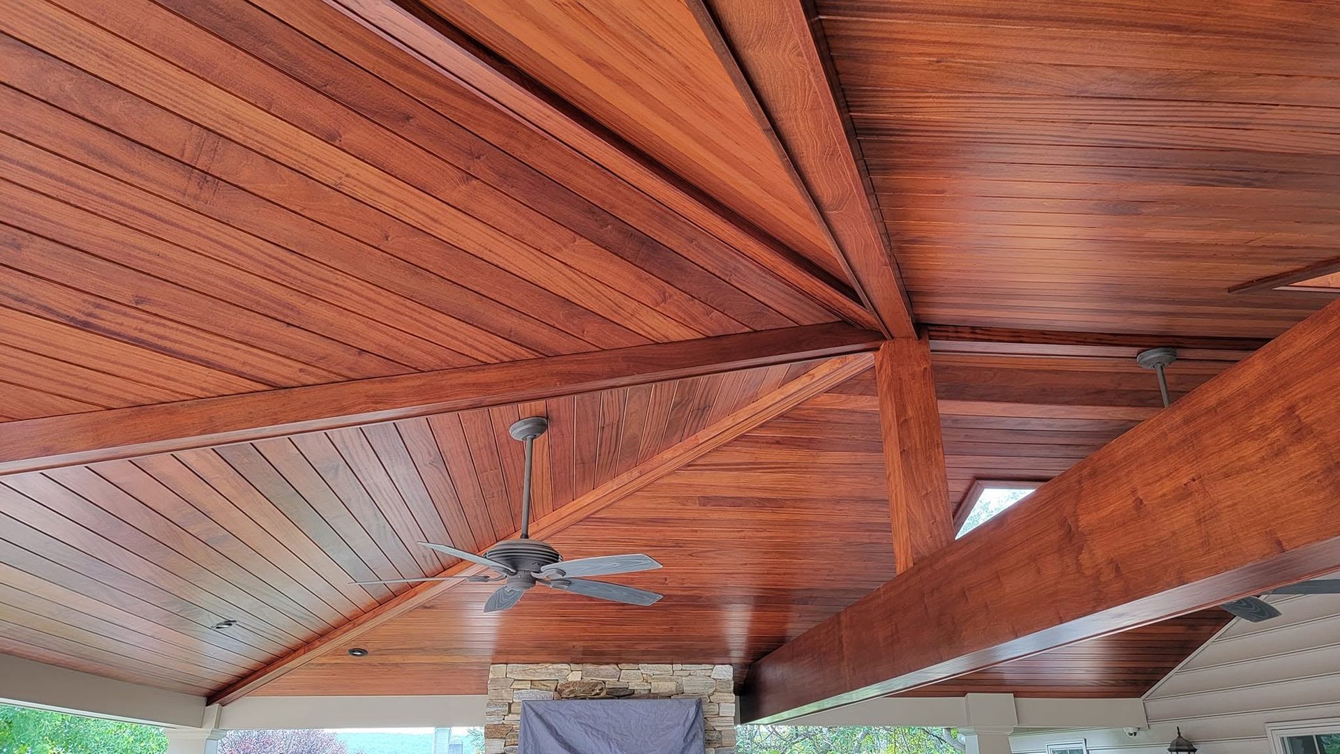 Wooden vaulted ceiling with exposed beams and a ceiling fan in a covered outdoor patio