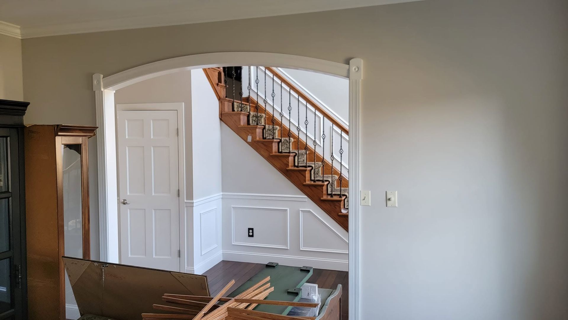 Interior entryway with white arched doorway, staircase, and gray walls in a house.