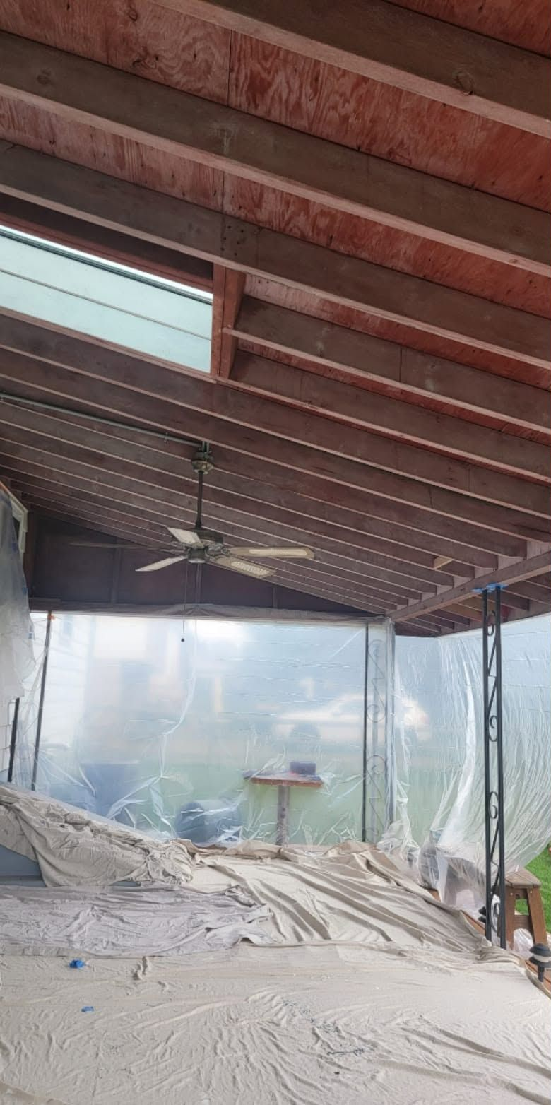 Dusty covered porch with exposed beams, ceiling fan, hanging lights, and screened view of an outdoor yard