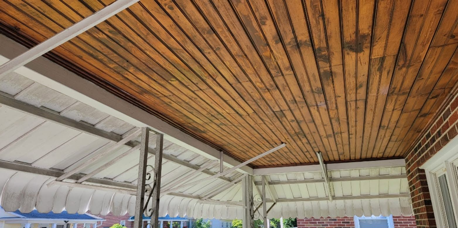 Wooden ceiling with exposed beams over an open-air structure and white support columns