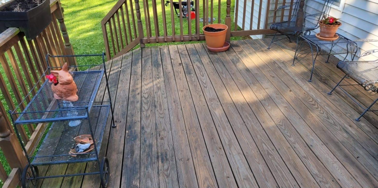 Wooden backyard deck with two small tables holding potted plants and a grill in the corner.