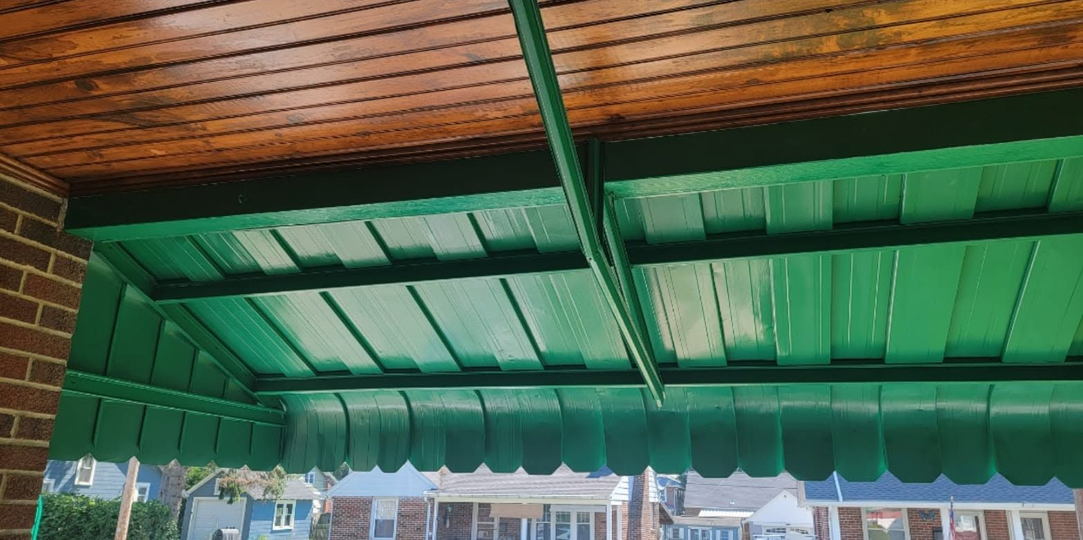 Green awning and brick storefront view with striped canopy and metal support beam