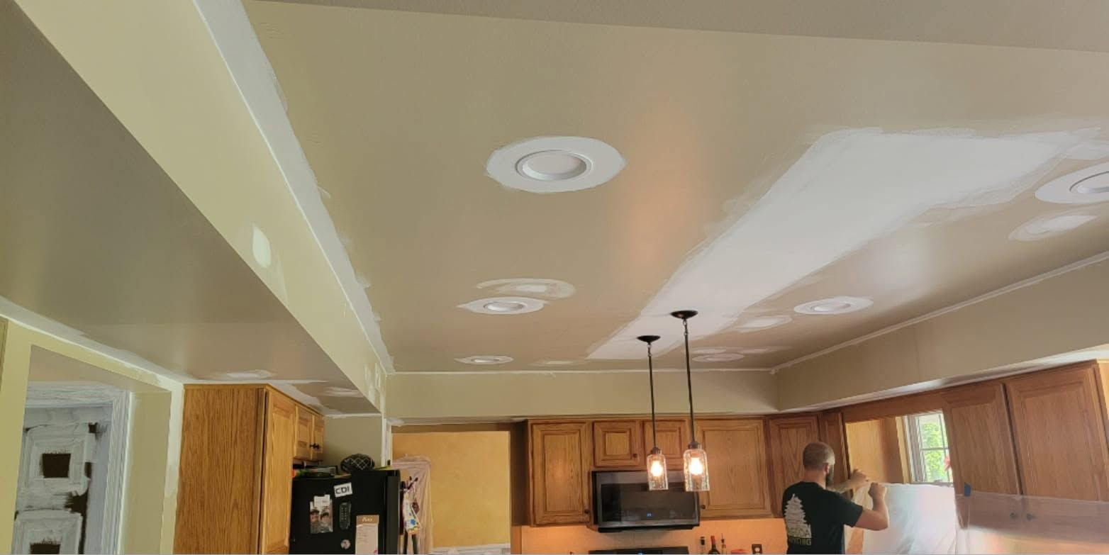 Bright kitchen with wood cabinets, recessed lights, and a person standing near the counter