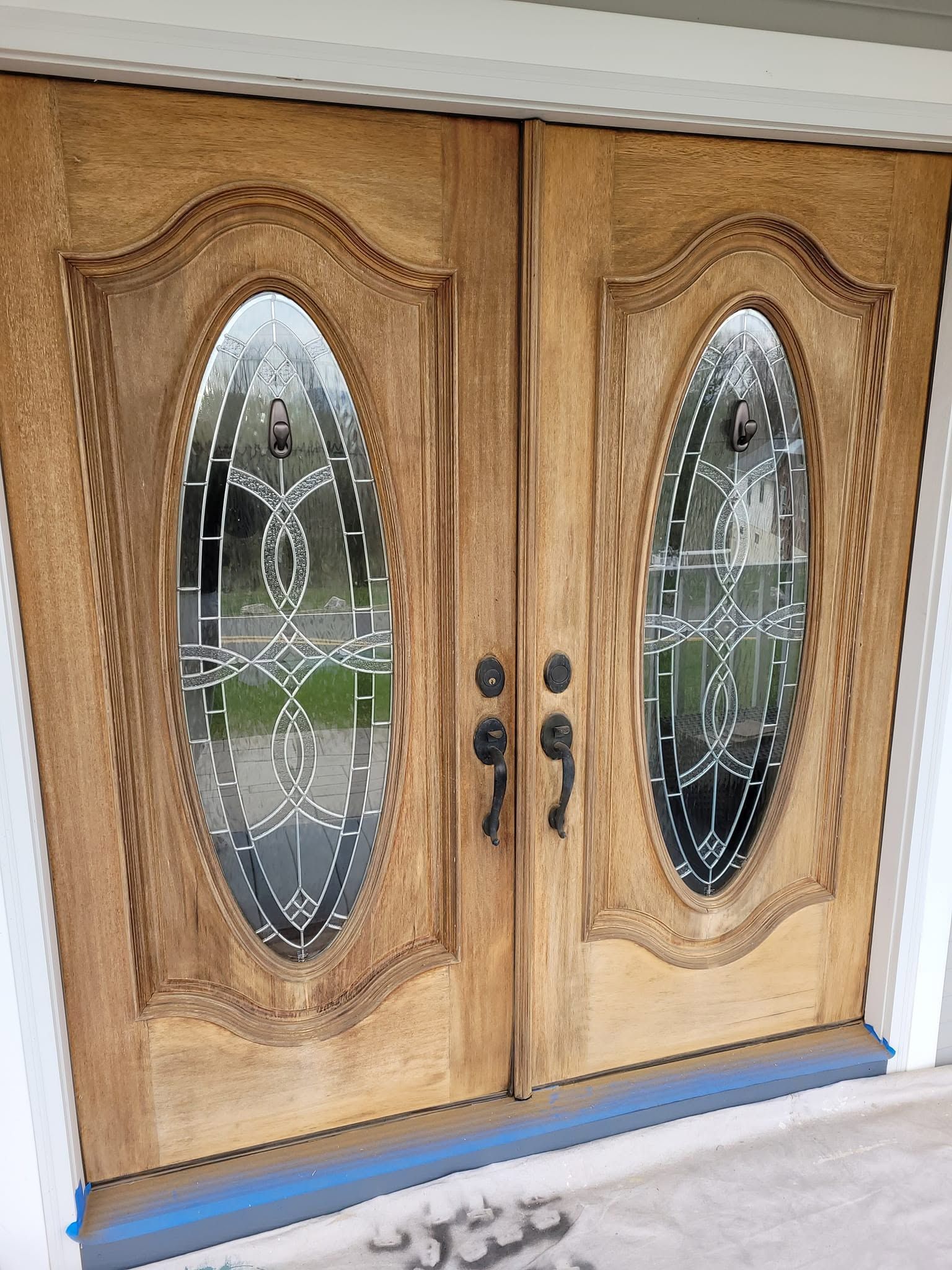 Wooden double front doors with oval frosted glass panels and ornate carved trim