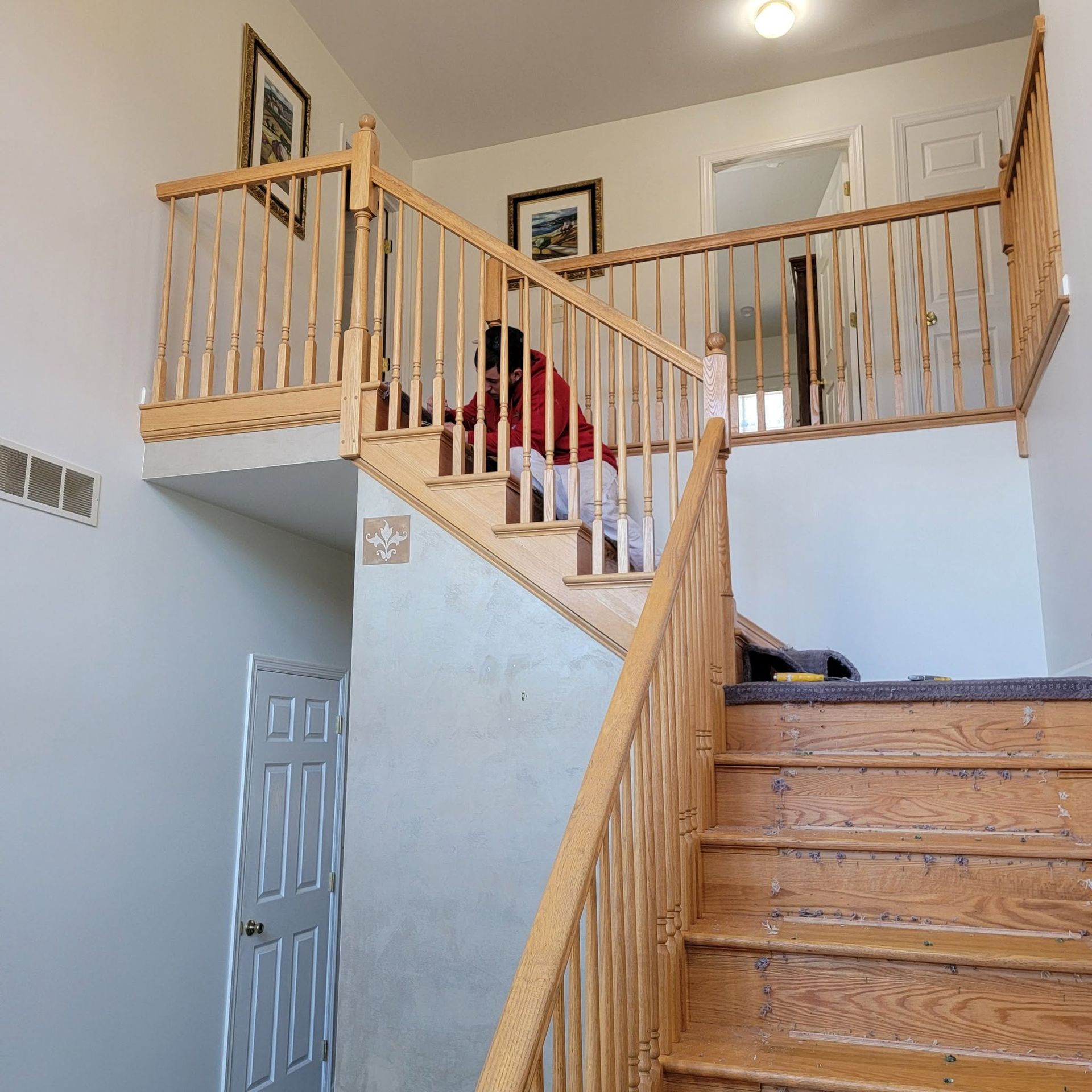 Staircase with wooden railings leading to an upper landing in a bright home interior