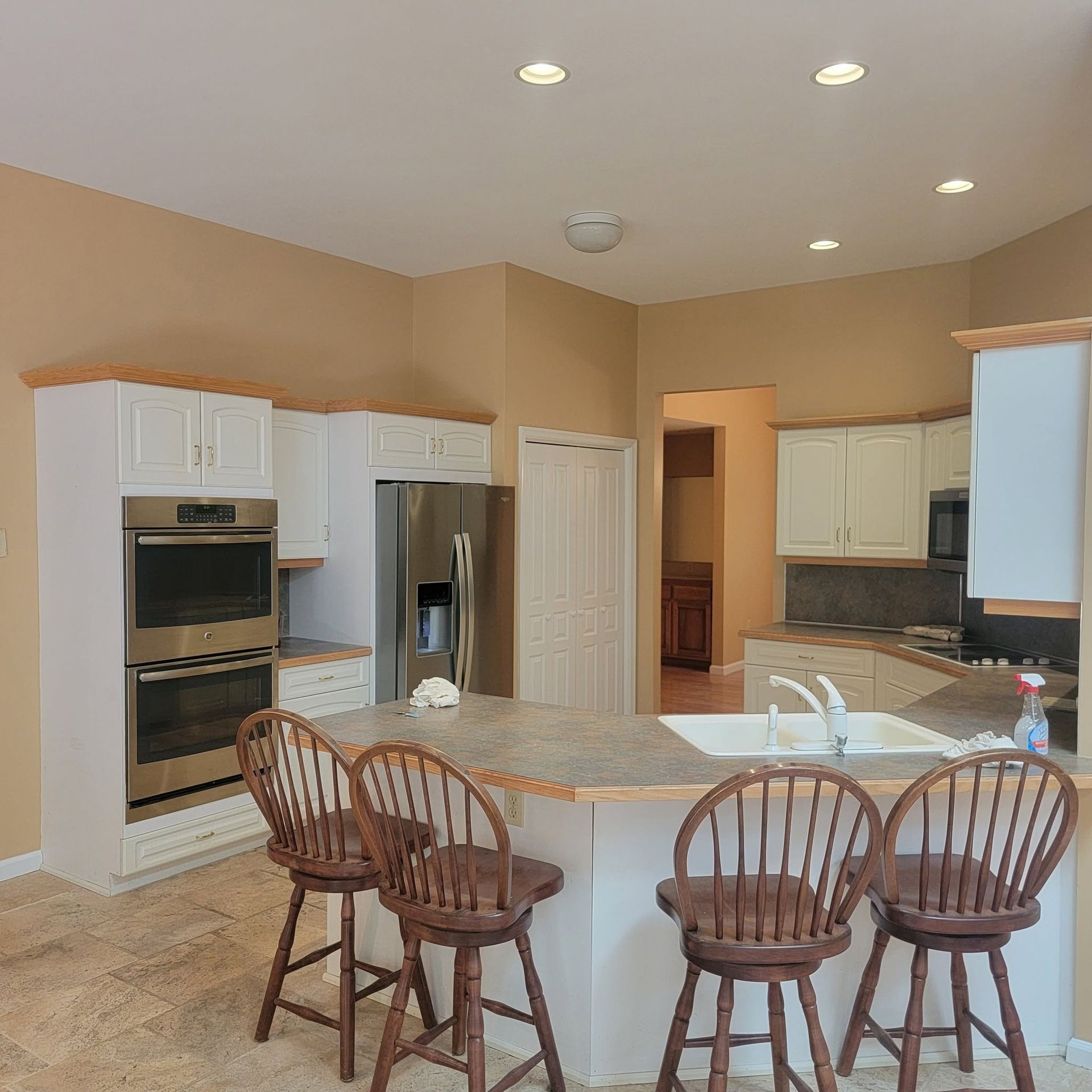 Bright kitchen with white cabinets, granite island, and four wooden bar stools