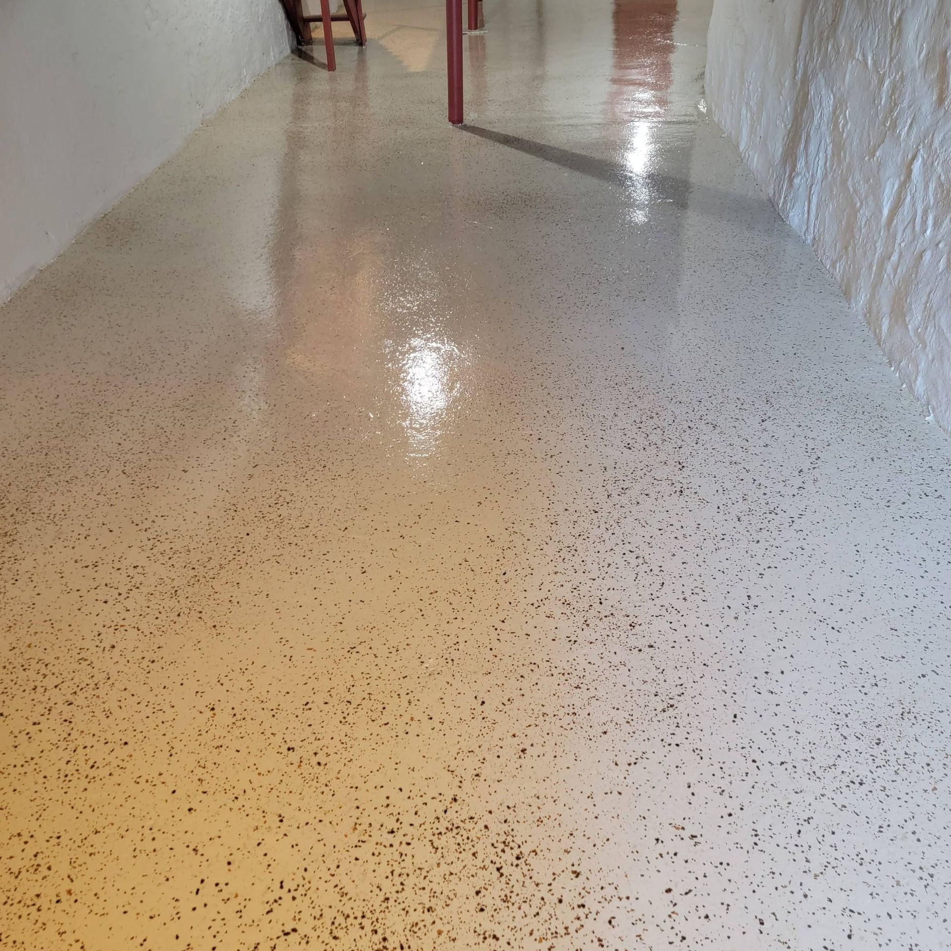 Shiny speckled floor in a hallway with white walls and a door in the distance