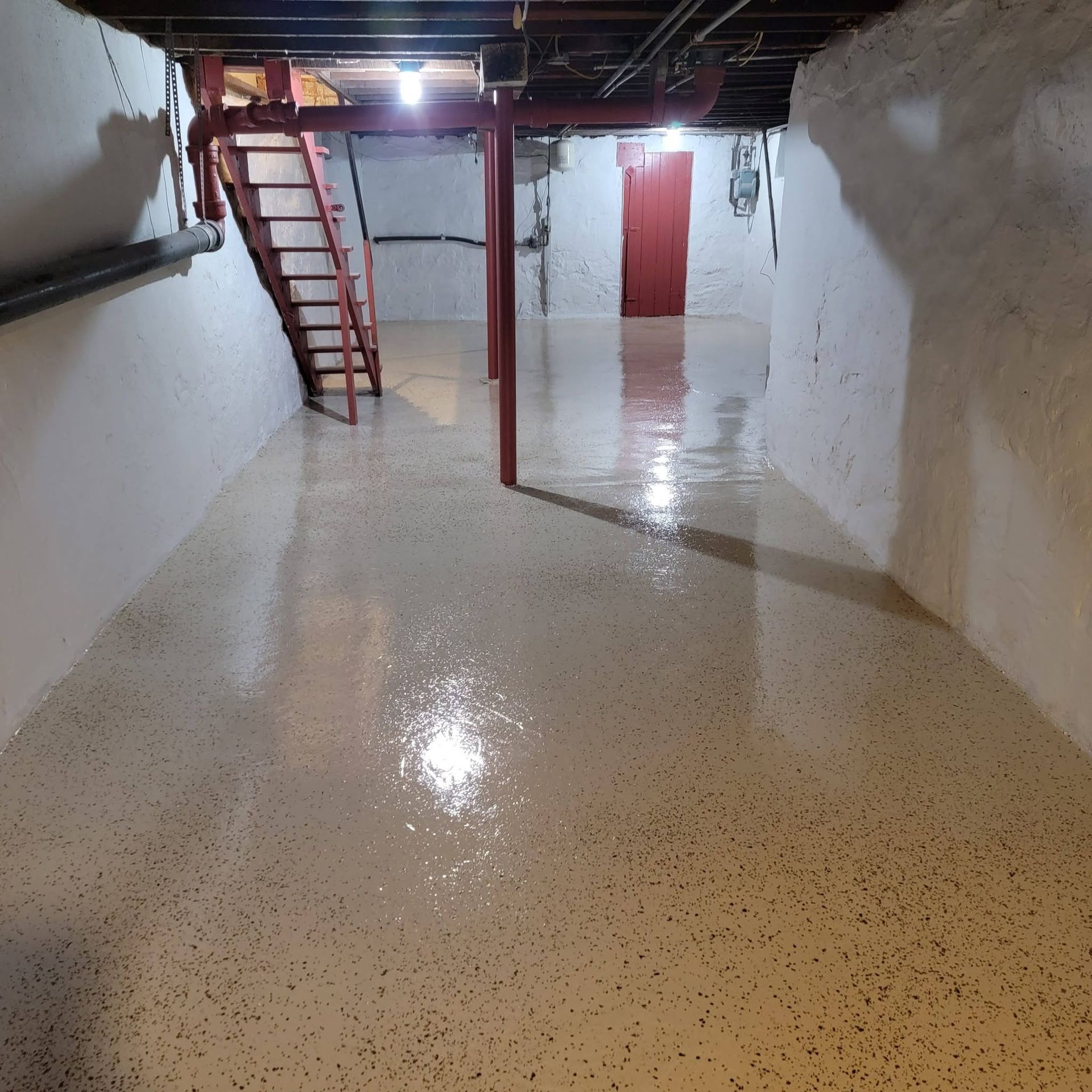 Basement with glossy white floor, red stairs, and exposed ceiling pipes and beams