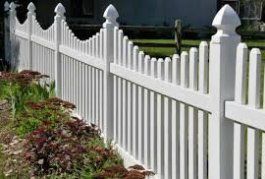 A white picket fence surrounds a lush green yard.