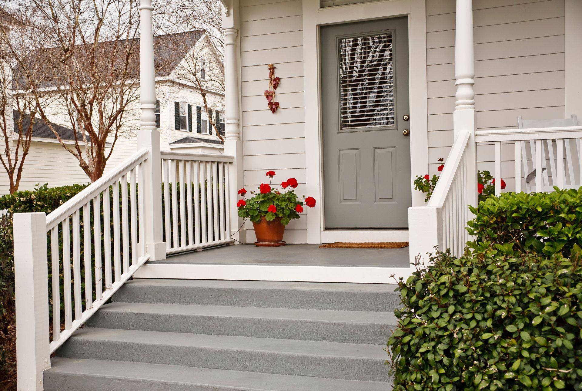 A white house with a porch and stairs leading to the front door.