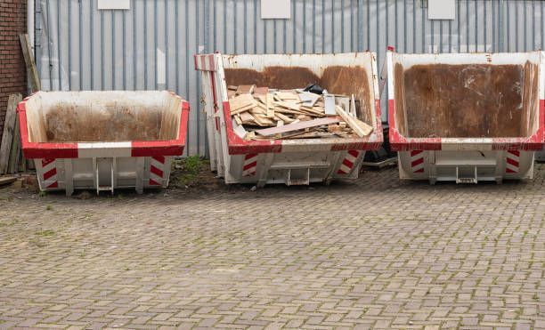 Three dumpsters are parked next to each other on a brick driveway.