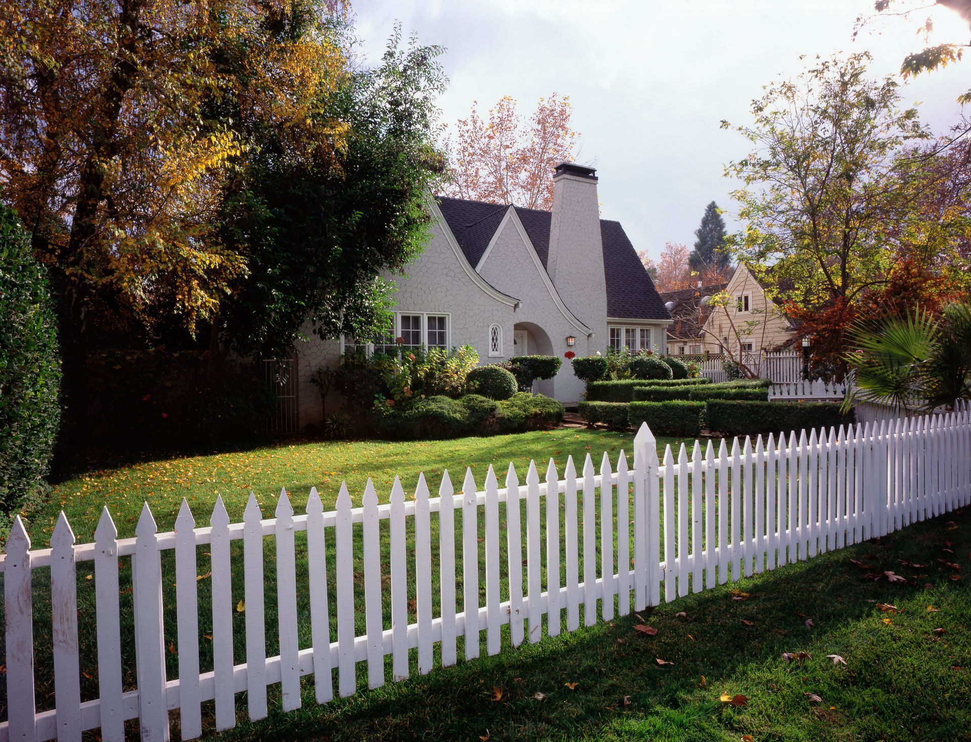 A white picket fence surrounds a white house
