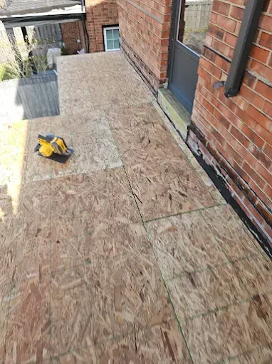 A white house with a green roof and two windows.