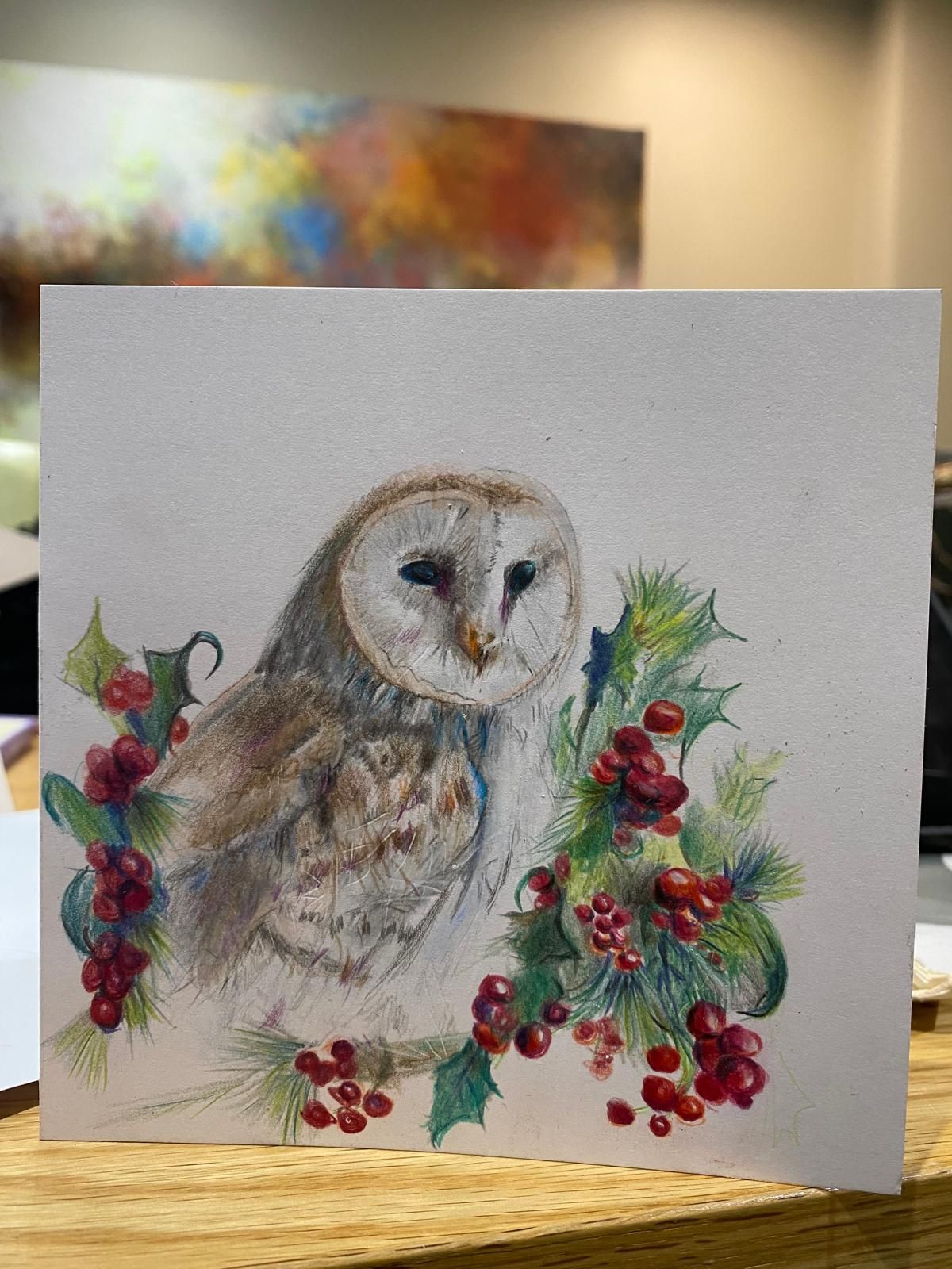 Barn owl with holly berries and leaves on a card. Creamy feathers, red berries, green leaves.