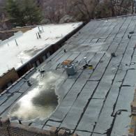 Flat roofs, one dark grey, one white, with standing water.