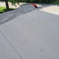 Flat roof with asphalt shingles, gray and black color.
