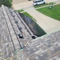 View of house roof with asphalt shingles, near driveway. Van parked on the road.