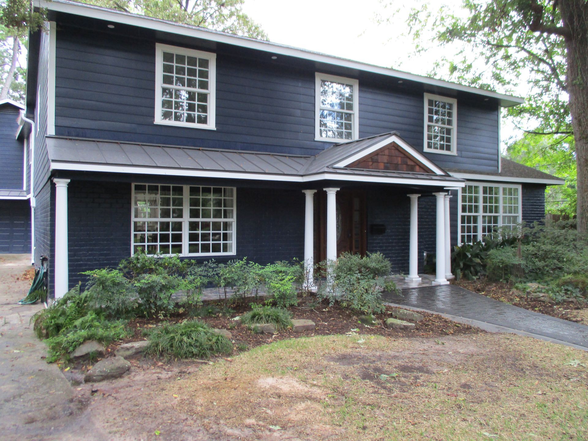 A large blue house with white pillars in front of it