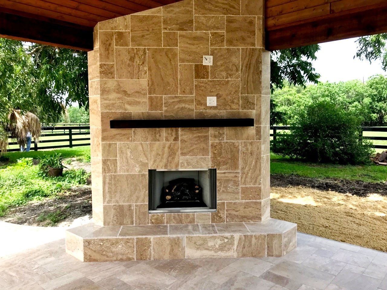 A stone fireplace with a mantle and a horse in the background