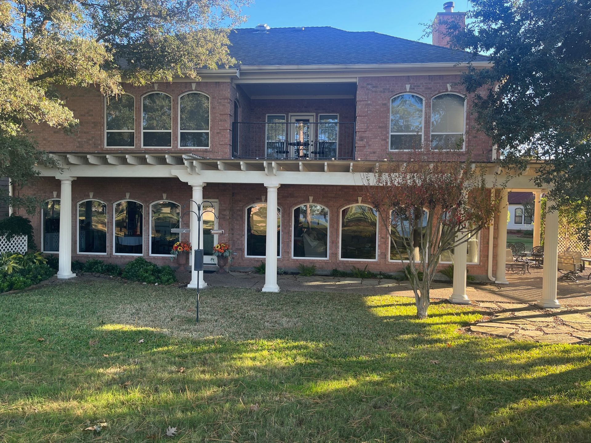 A large brick house with a pergola and lots of windows