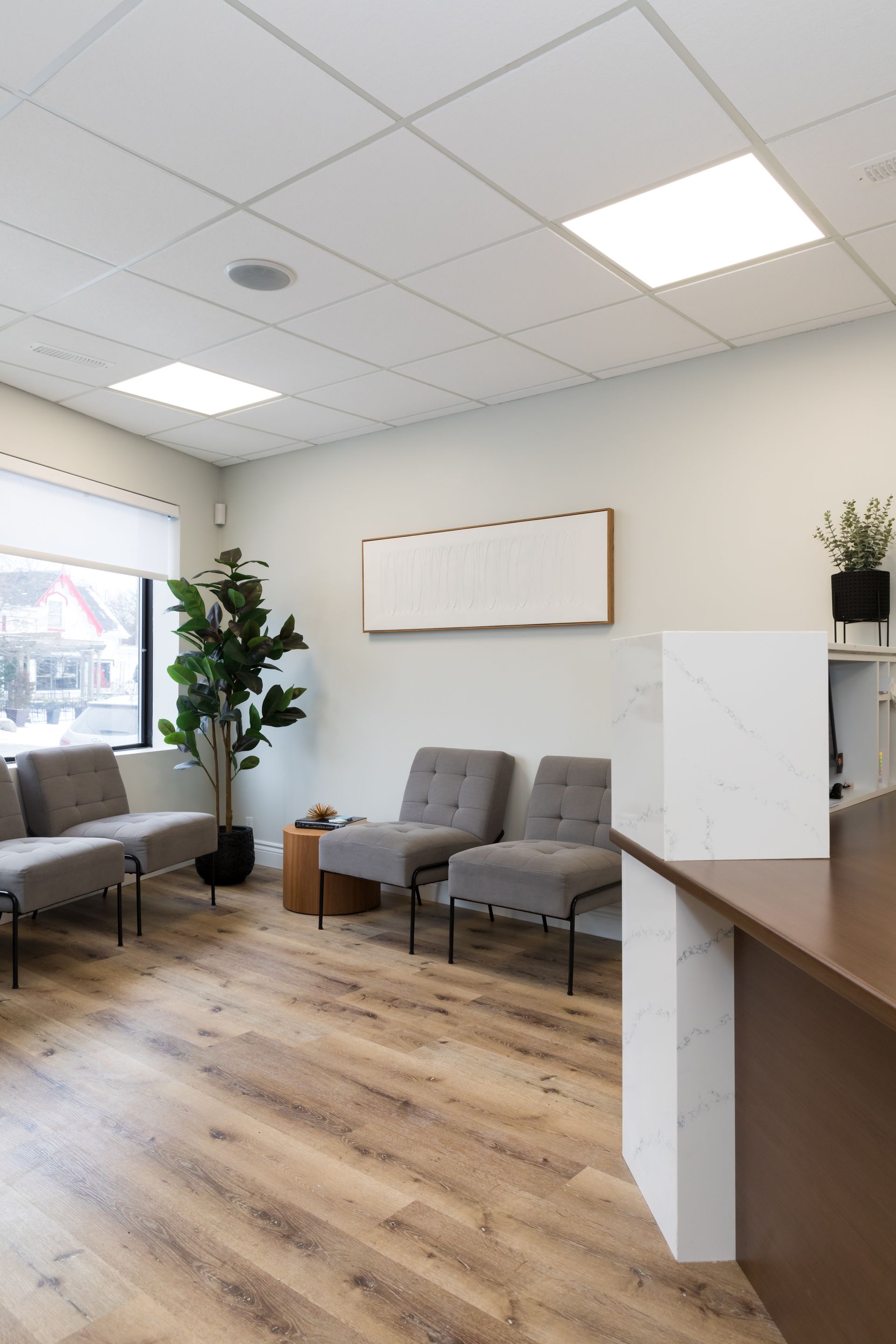 Reception area with grey chairs, wood floors, and a front desk.