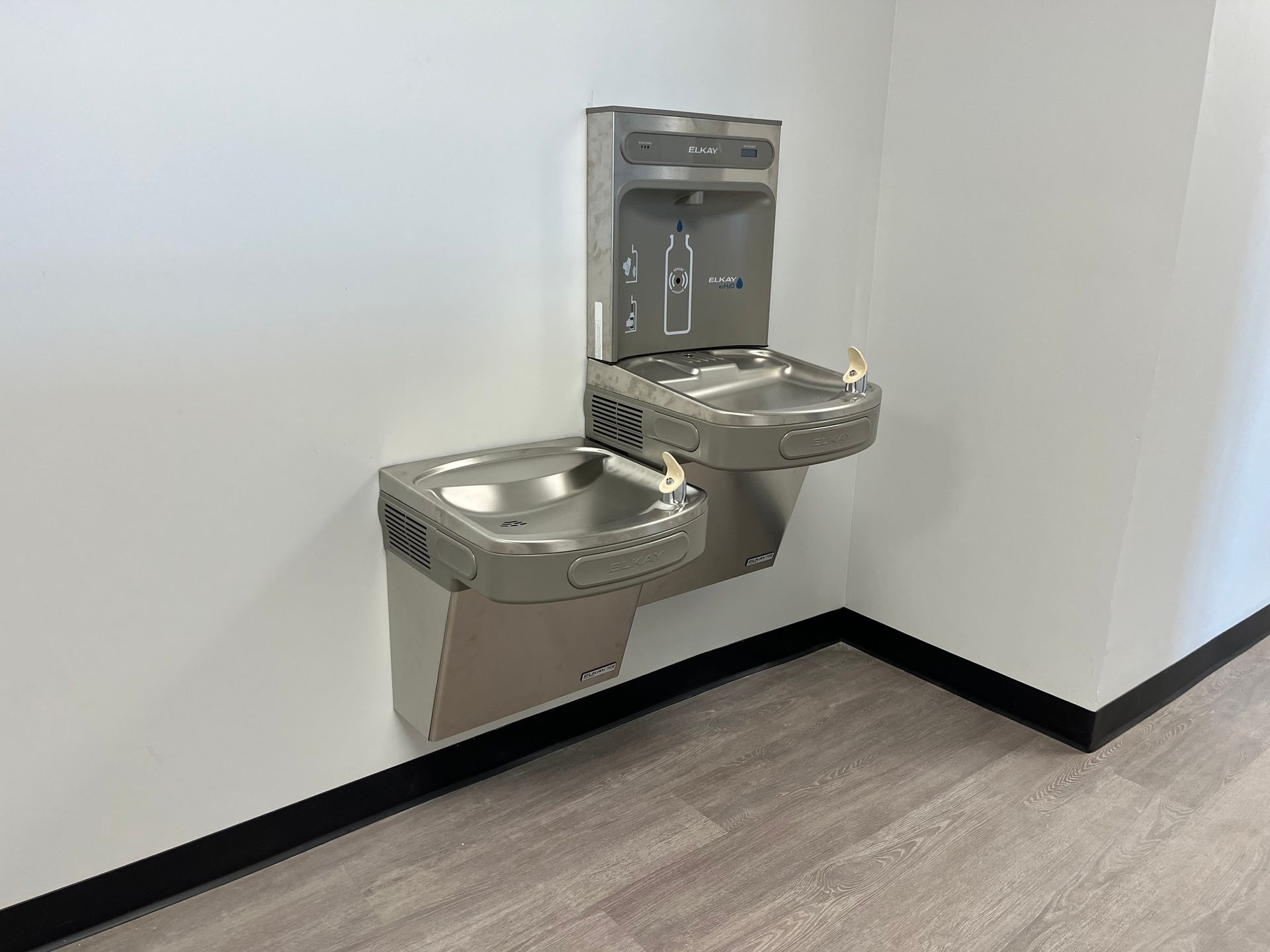 White radiator against a light green wall, in a room with light wooden flooring.